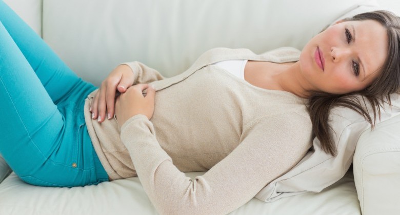 Anxious and sick woman lying on sofa