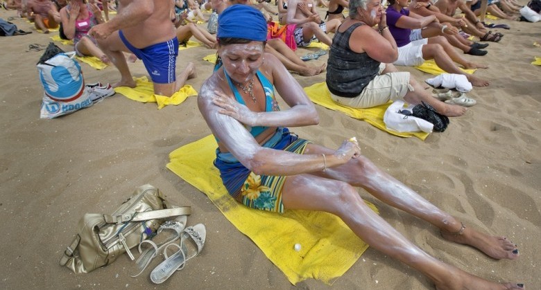 A woman applies sun cream on her body on the beach of Scheveningen, on July 21, 2010. About 250 sunbathers on a few square meters were appied sun cream at the same time on their body, to set a new Guiness Book Record. AFP PHOTO / ANP / KOEN SUYK netherlands out - belgium out (Photo credit should read KOEN SUYK/AFP/Getty Images)