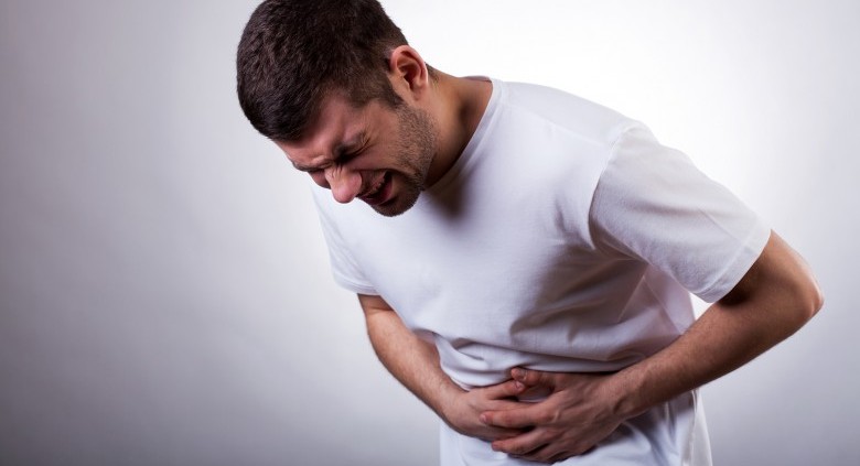 Young man with severe stomach ache holding his stomach