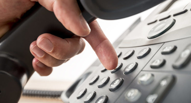 Closeup of dialing a telephone number on a black landline telephone. Conceptual of global communication, business support and customer care.