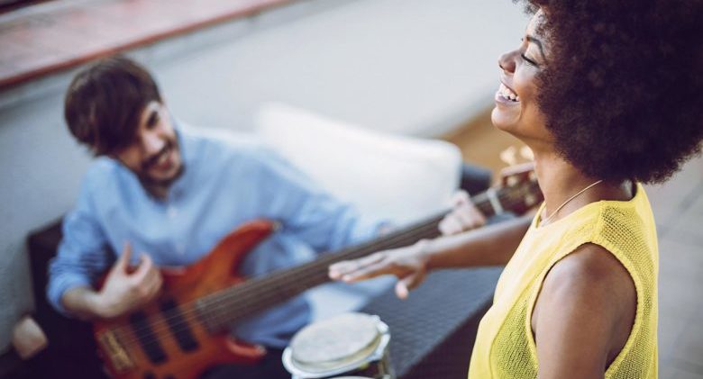 Multirracial young couple playing drums and a guitar