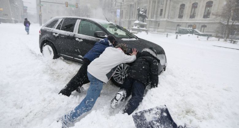 Good Samaritans help a stuck motorist in front of City Hall in Philadelphia as snow falls over the region Saturday, Jan. 23, 2016. (David Swanson/Philadelphia Daily News via AP) MANDATORY CREDIT