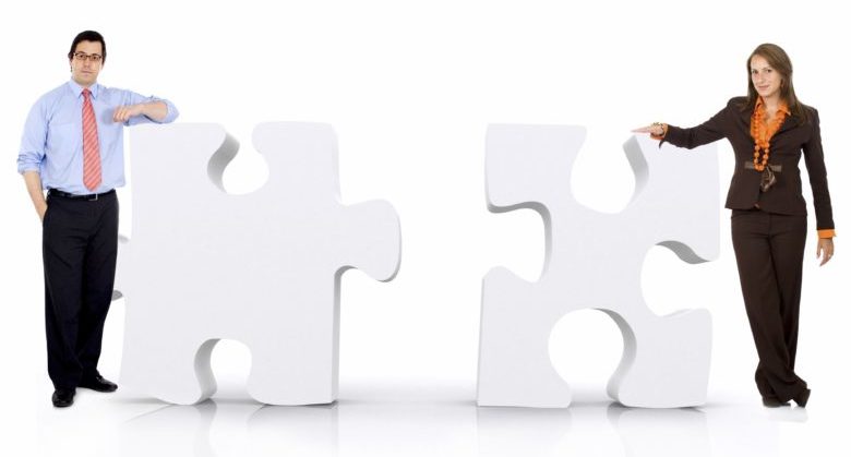 business partnership of a couple of businesspeople leaning on puzzle pieces isolated over a white background